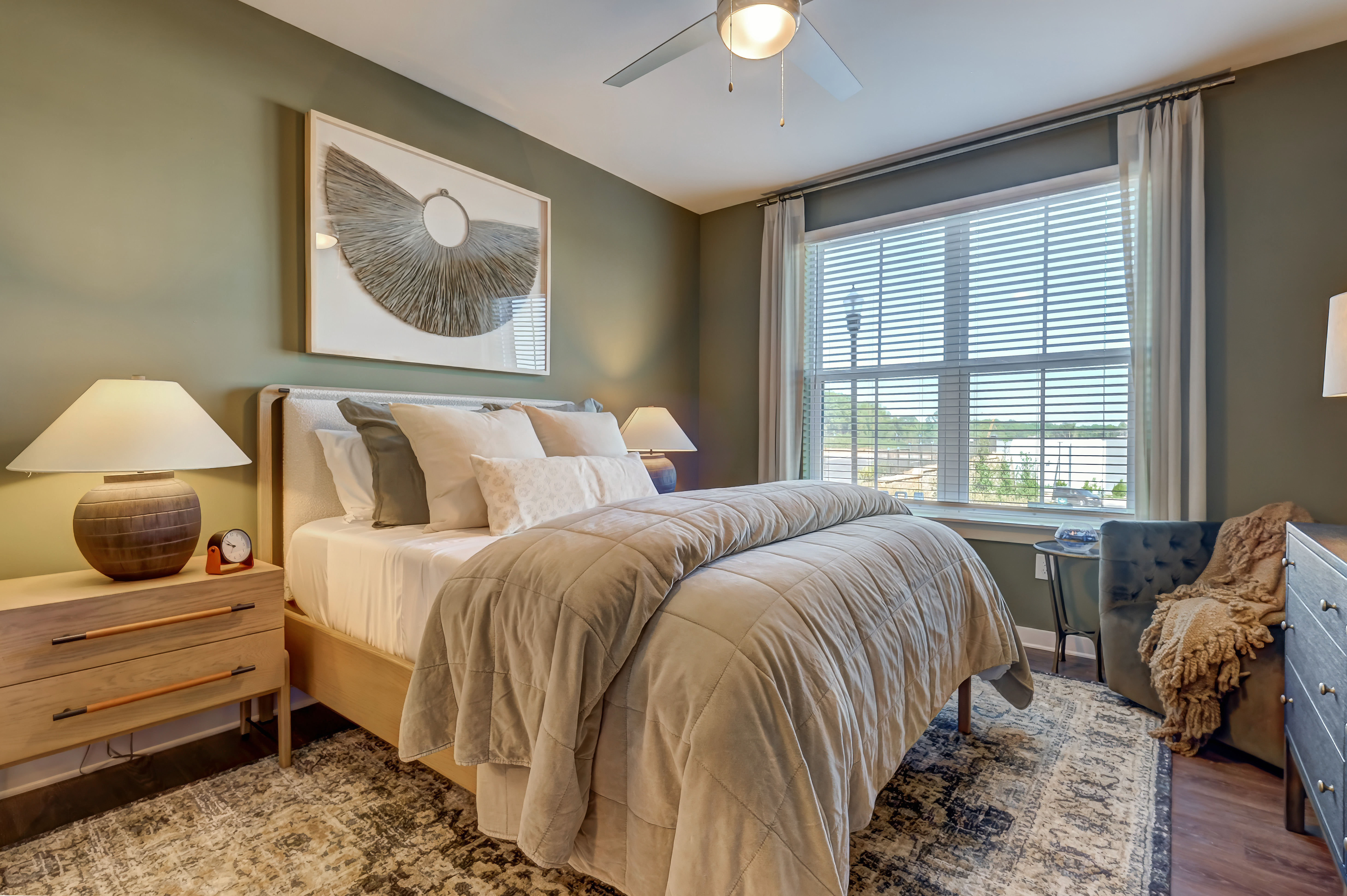 Modern bedroom with large window, neutral decor, and cozy bedding in upscale apartment.