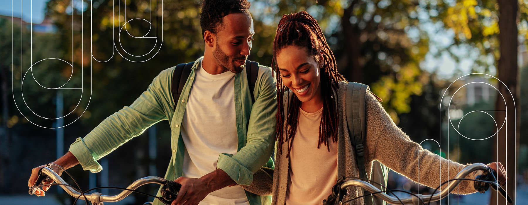 young couple walk their bicycles in a park